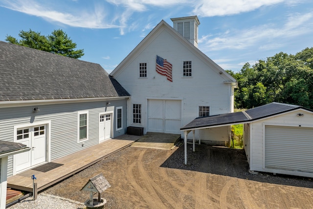 rear view of house with an outdoor structure, a garage, and a deck