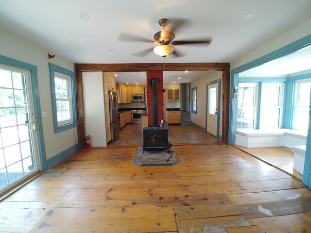 unfurnished living room featuring light hardwood / wood-style flooring, ceiling fan, and a wood stove