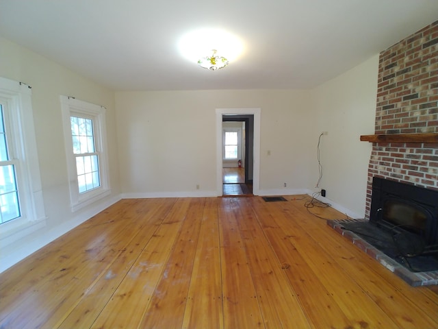 unfurnished living room featuring a wealth of natural light, light hardwood / wood-style flooring, and a fireplace