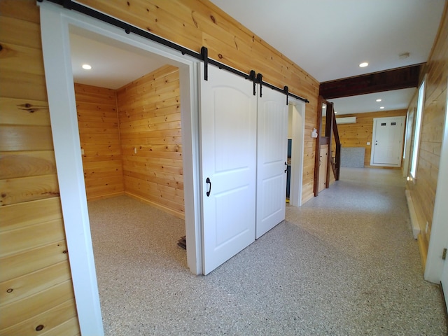 corridor with a barn door and wood walls