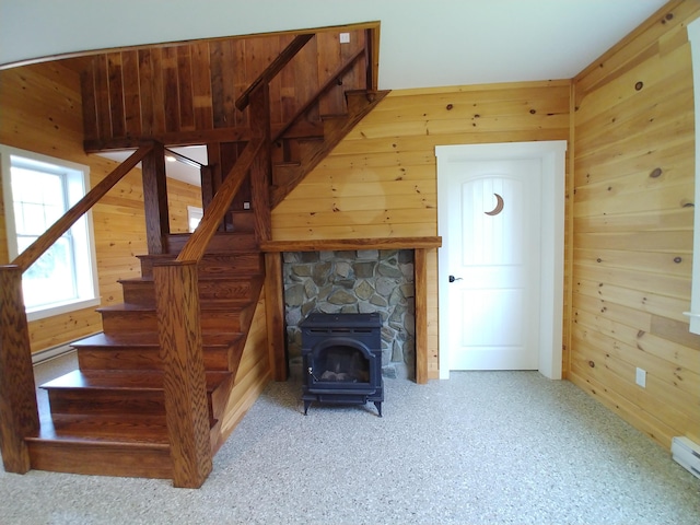 staircase featuring a wood stove, wood walls, and a fireplace