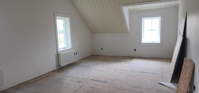 bonus room featuring radiator, plenty of natural light, and vaulted ceiling