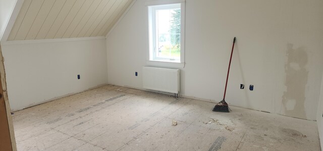 bonus room featuring lofted ceiling and radiator