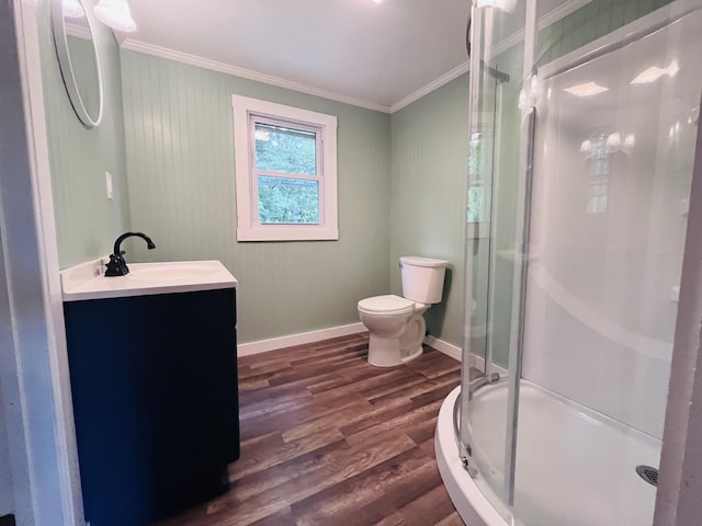 bathroom featuring a shower with door, hardwood / wood-style floors, vanity, ornamental molding, and toilet