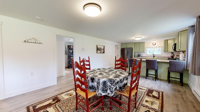 dining area with light hardwood / wood-style floors and stacked washer / drying machine