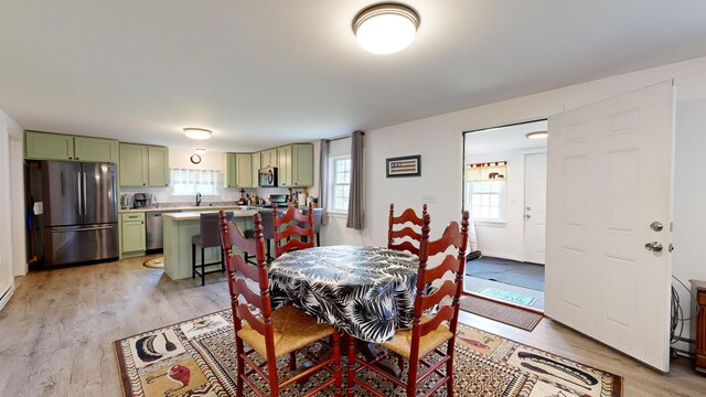 dining space with light wood-type flooring, a wealth of natural light, and sink