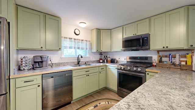 kitchen featuring green cabinets, stainless steel appliances, light hardwood / wood-style floors, and sink