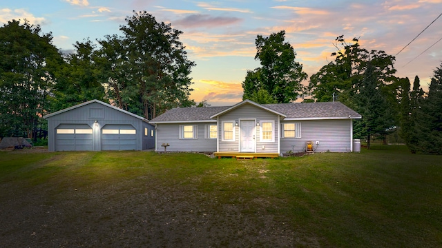 ranch-style house with a garage, a yard, and an outbuilding