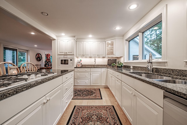 kitchen with white cabinetry, a wealth of natural light, white appliances, and light wood-type flooring