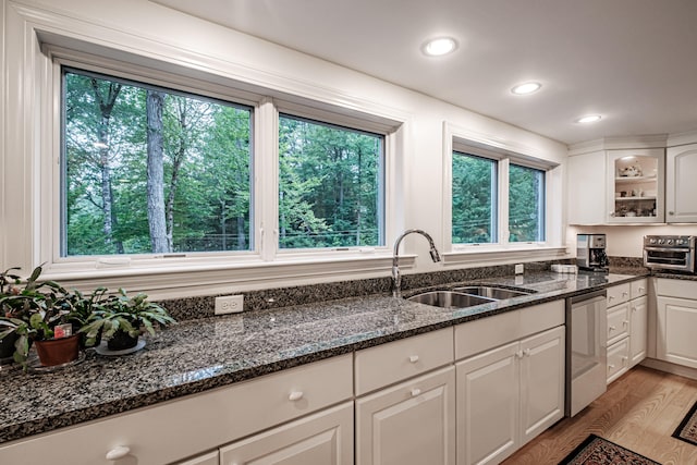 kitchen featuring sink, dark stone countertops, white cabinets, and light wood-type flooring