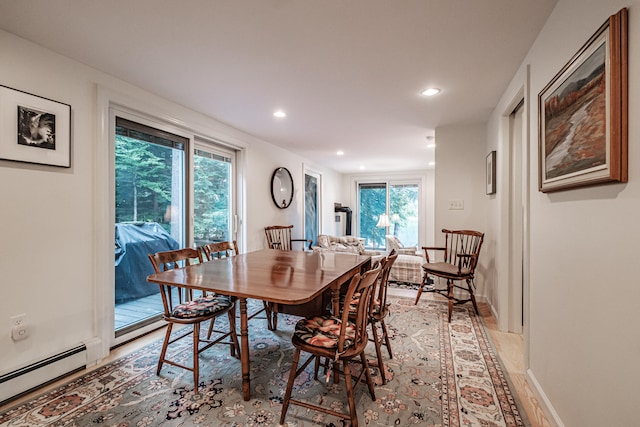 dining area featuring light hardwood / wood-style flooring, a healthy amount of sunlight, and a baseboard heating unit