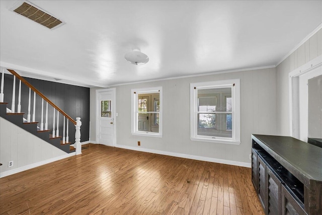 unfurnished living room featuring wood-type flooring and crown molding