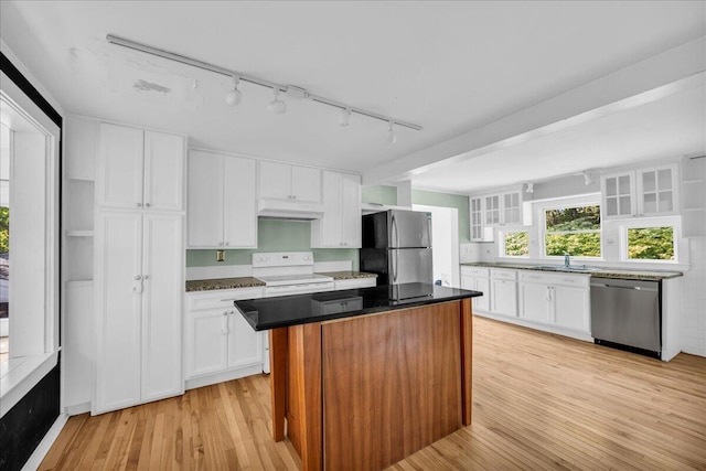 kitchen with appliances with stainless steel finishes, rail lighting, white cabinetry, a center island, and light hardwood / wood-style flooring