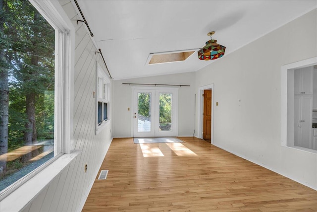 spare room with light hardwood / wood-style flooring, vaulted ceiling, and french doors