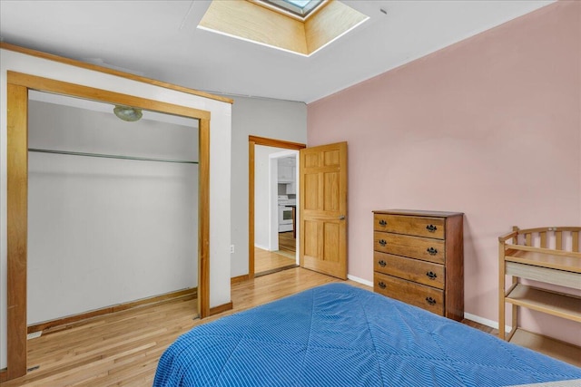 bedroom featuring light wood-type flooring, a skylight, and a closet