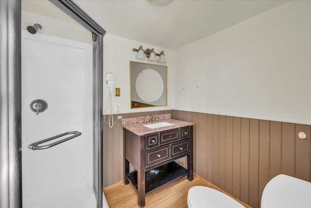 bathroom with walk in shower, hardwood / wood-style flooring, vanity, and toilet