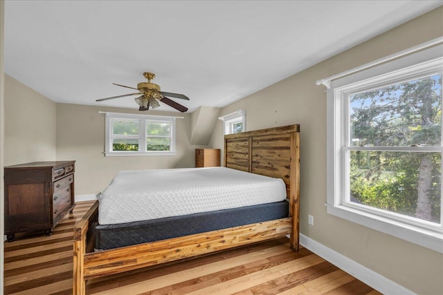 bedroom with multiple windows, wood-type flooring, and ceiling fan