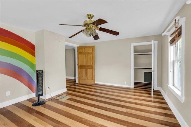 empty room featuring a wealth of natural light, ceiling fan, and hardwood / wood-style flooring