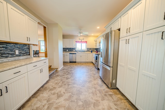 kitchen with stainless steel appliances, sink, decorative backsplash, white cabinetry, and ceiling fan