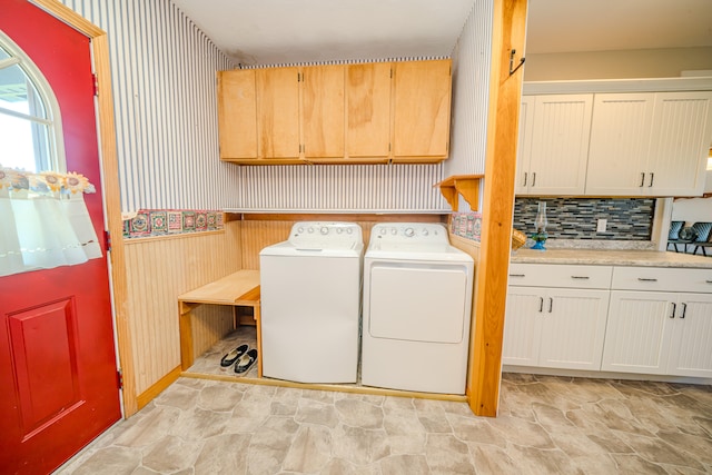 laundry room featuring wood walls, cabinets, and washer and clothes dryer