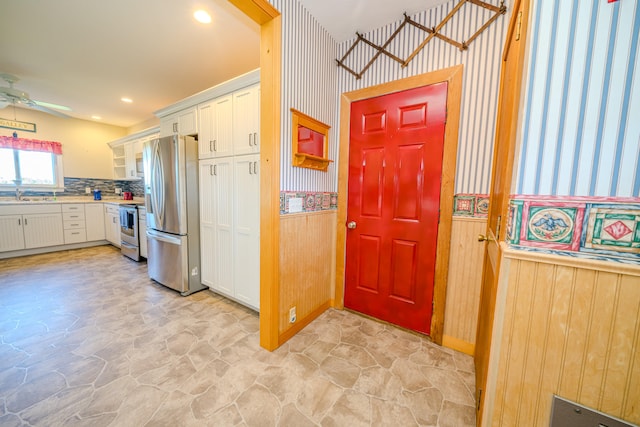 kitchen with appliances with stainless steel finishes, tasteful backsplash, sink, ceiling fan, and white cabinets