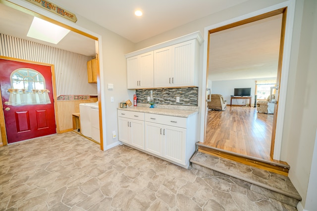 kitchen with light hardwood / wood-style floors, light stone counters, white cabinets, and tasteful backsplash