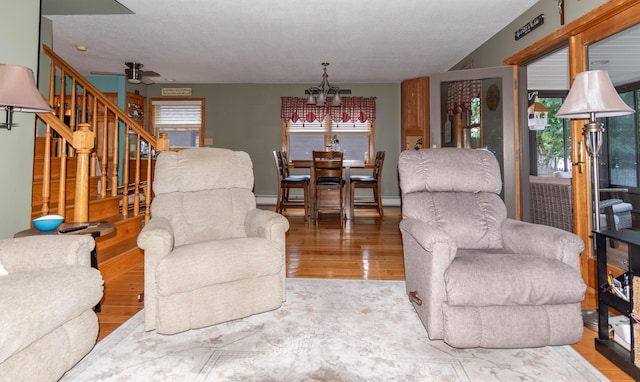 803 Lake Shore Rd, Madawaska, ME 04773 - living room with a baseboard radiator, stairway, a chandelier, and wood finished floors