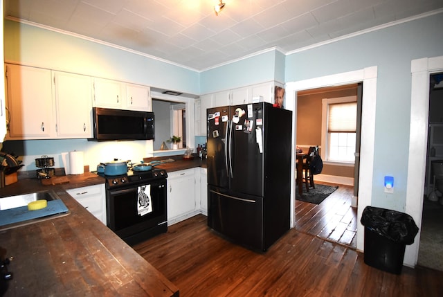 kitchen featuring dark wood-type flooring, crown molding, white cabinetry, and black appliances