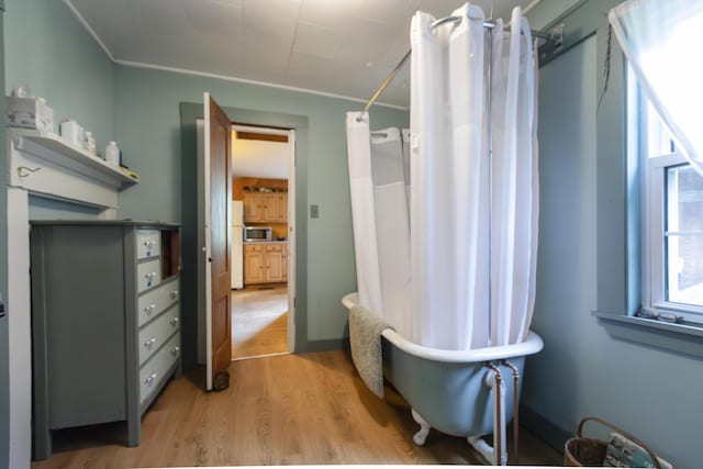 full bath featuring a tub to relax in, a shower with curtain, and wood finished floors