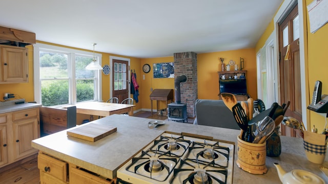 kitchen featuring pendant lighting, light countertops, a wood stove, white range with gas cooktop, and wood finished floors