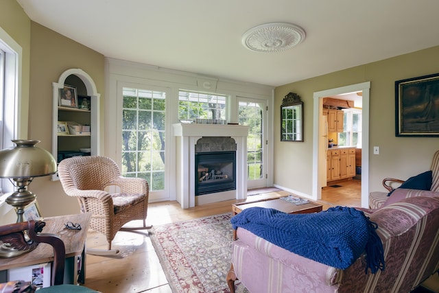 living area featuring baseboards and a glass covered fireplace