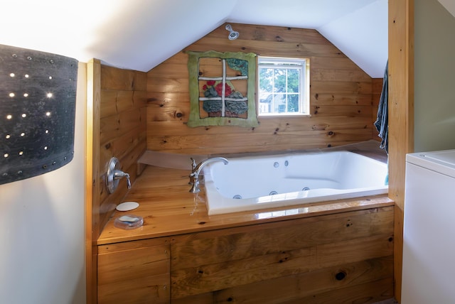 bathroom with lofted ceiling, washer / clothes dryer, wood walls, and a tub with jets