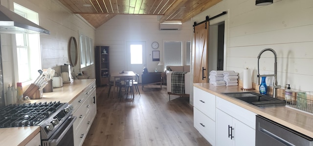 kitchen with white cabinets, wood ceiling, dishwashing machine, a barn door, and wall chimney exhaust hood