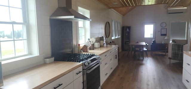 kitchen with gas stove, light wood-type flooring, white cabinets, and wall chimney exhaust hood