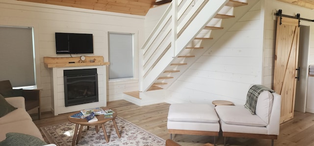 524A Ridge Rd, Oakfield, ME 04780 - living room with light wood finished floors, a barn door, wood walls, and stairway