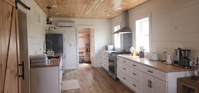 kitchen with white cabinetry, stainless steel range with gas cooktop, wooden ceiling, light wood-type flooring, and wall chimney exhaust hood