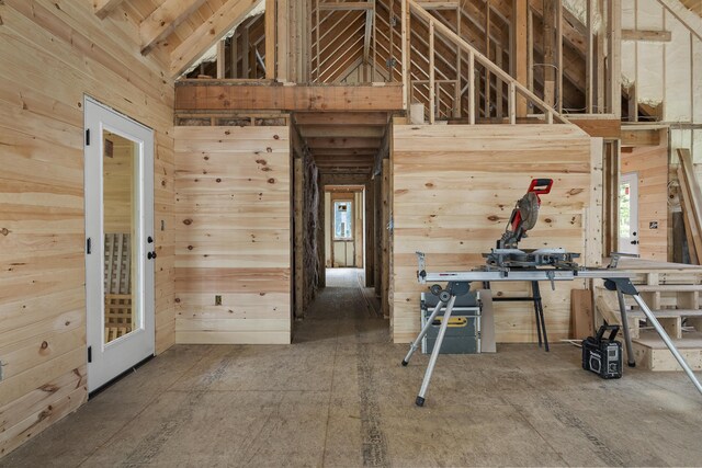 interior space featuring vaulted ceiling and wooden walls