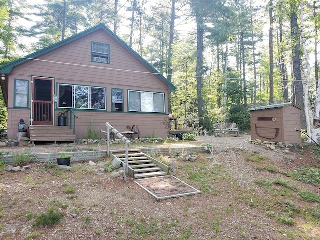 rear view of house featuring a storage shed