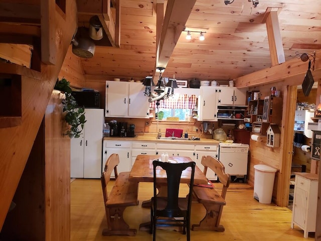 kitchen with wood walls, sink, white cabinets, and light hardwood / wood-style floors