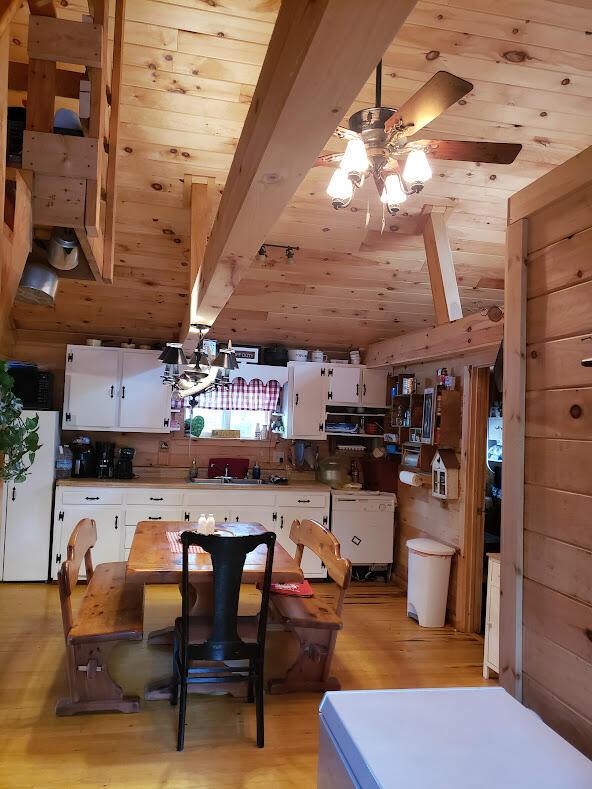 kitchen with white cabinetry, white fridge, wooden walls, ceiling fan, and light hardwood / wood-style floors