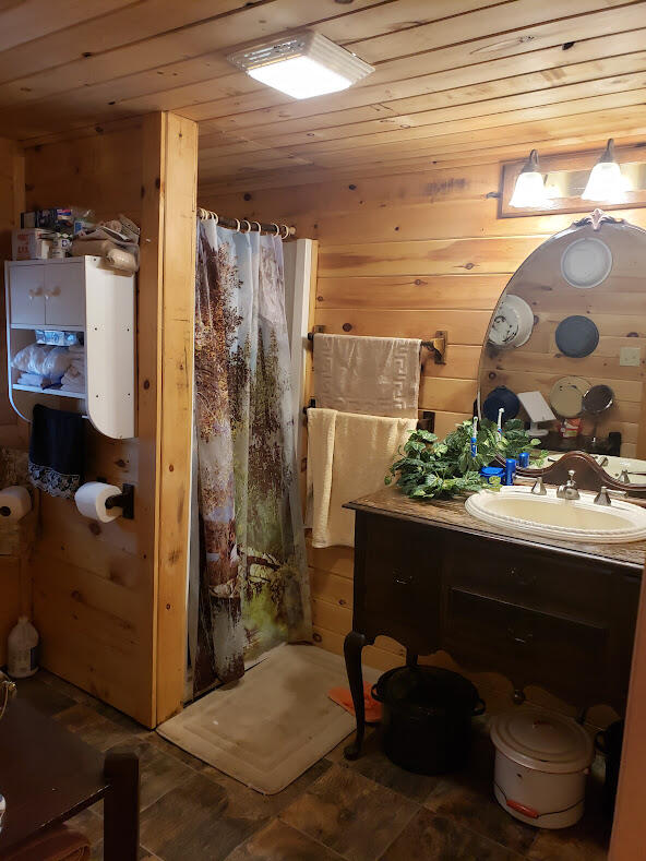 bathroom with tile patterned floors, wood walls, vanity, and wooden ceiling