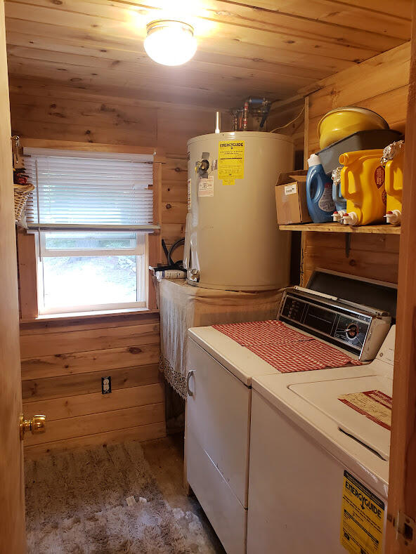 laundry room with wood ceiling, wood walls, water heater, and independent washer and dryer