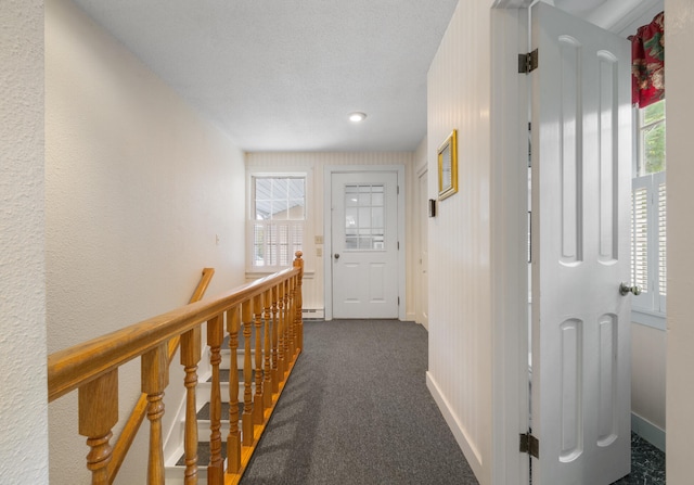 corridor featuring a textured ceiling, carpet, and a healthy amount of sunlight