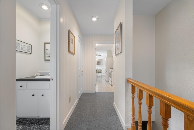 hallway with sink and light colored carpet