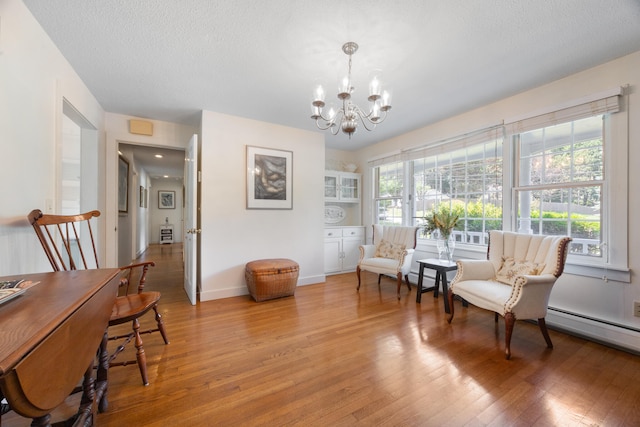 sitting room featuring a notable chandelier, hardwood / wood-style flooring, and a textured ceiling