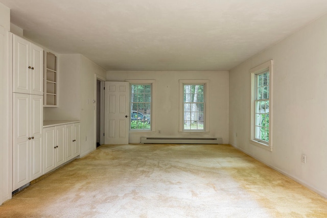 interior space with light carpet and a baseboard heating unit