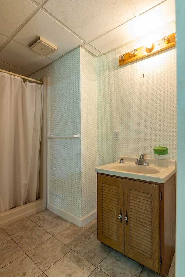 bathroom featuring tile patterned floors, vanity, and a drop ceiling