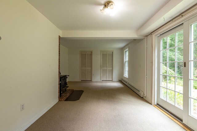 interior space featuring a baseboard heating unit, light carpet, and a wealth of natural light