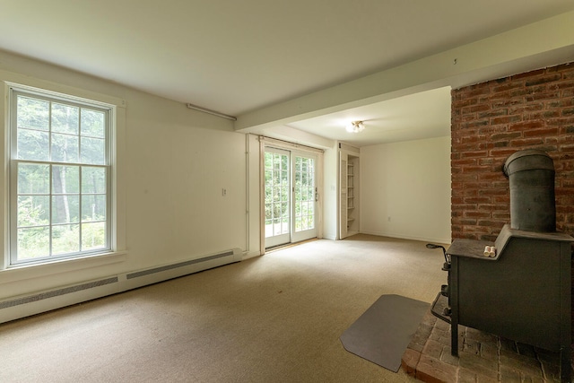 unfurnished living room featuring a wood stove, carpet flooring, plenty of natural light, and brick wall