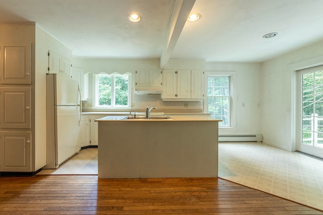 kitchen with baseboard heating, light tile patterned floors, a wealth of natural light, and white fridge